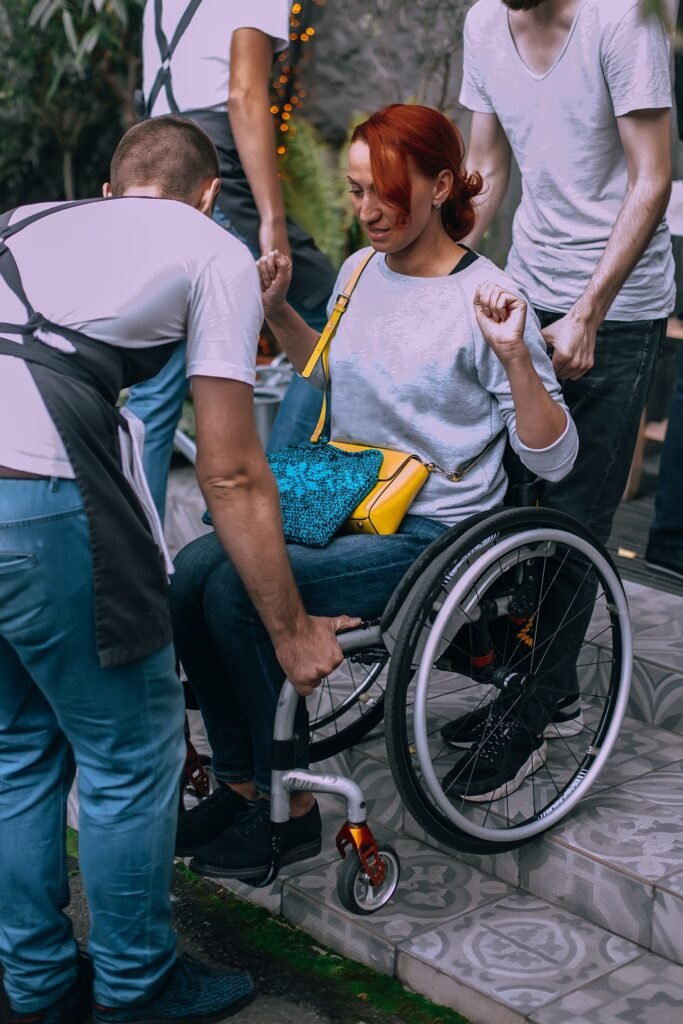 Woman in a wheelchair smiling while engaging with others in a friendly ndis community participation setting.