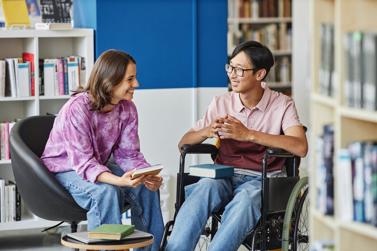 Woman smiling and talking with a man in a wheelchair – NDIS short term accommodation Sydney by Improved Ability.