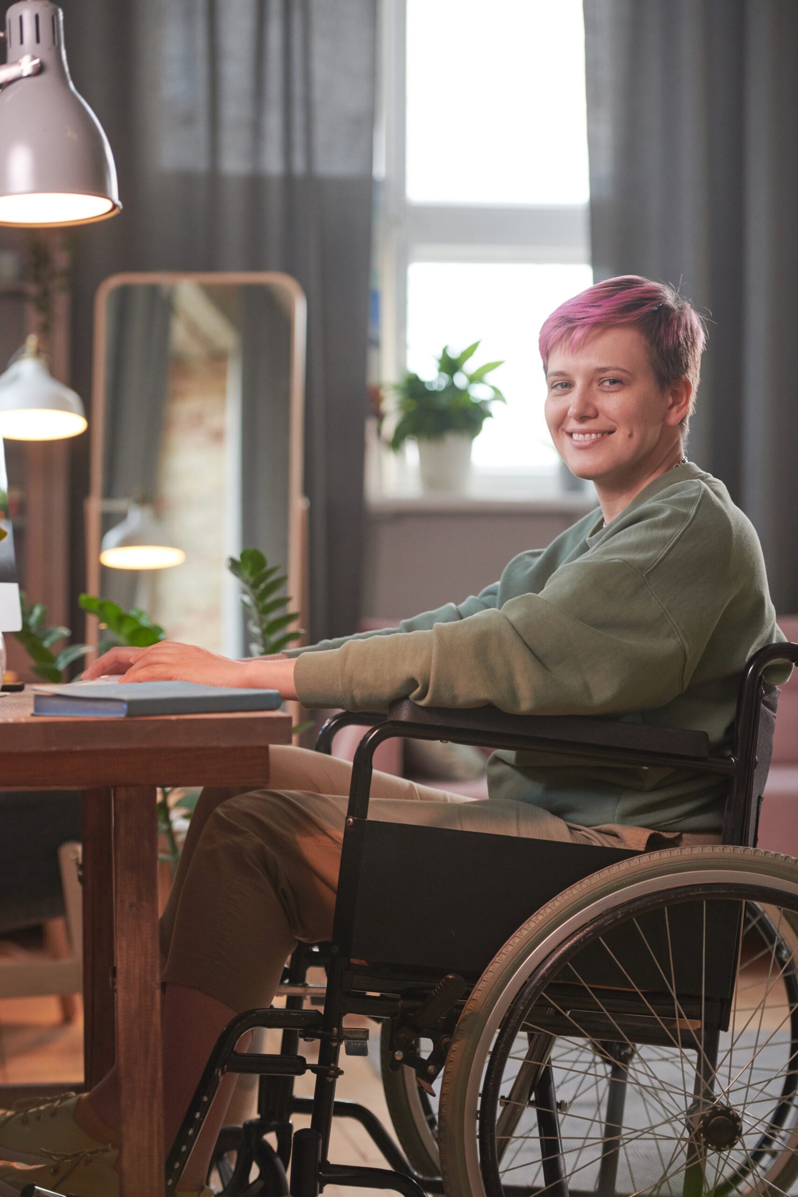 Young woman in a wheelchair smiling indoors, representing Supported Independent Living (SIL) services under the NDIS
